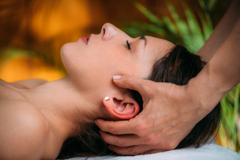 A CST therapist gently massaging a woman's head during a craniosacral therapy session, promoting stress relief.